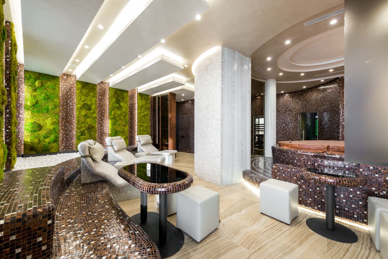A calm, upscale spa interior with mosaic tile and a living moss wall