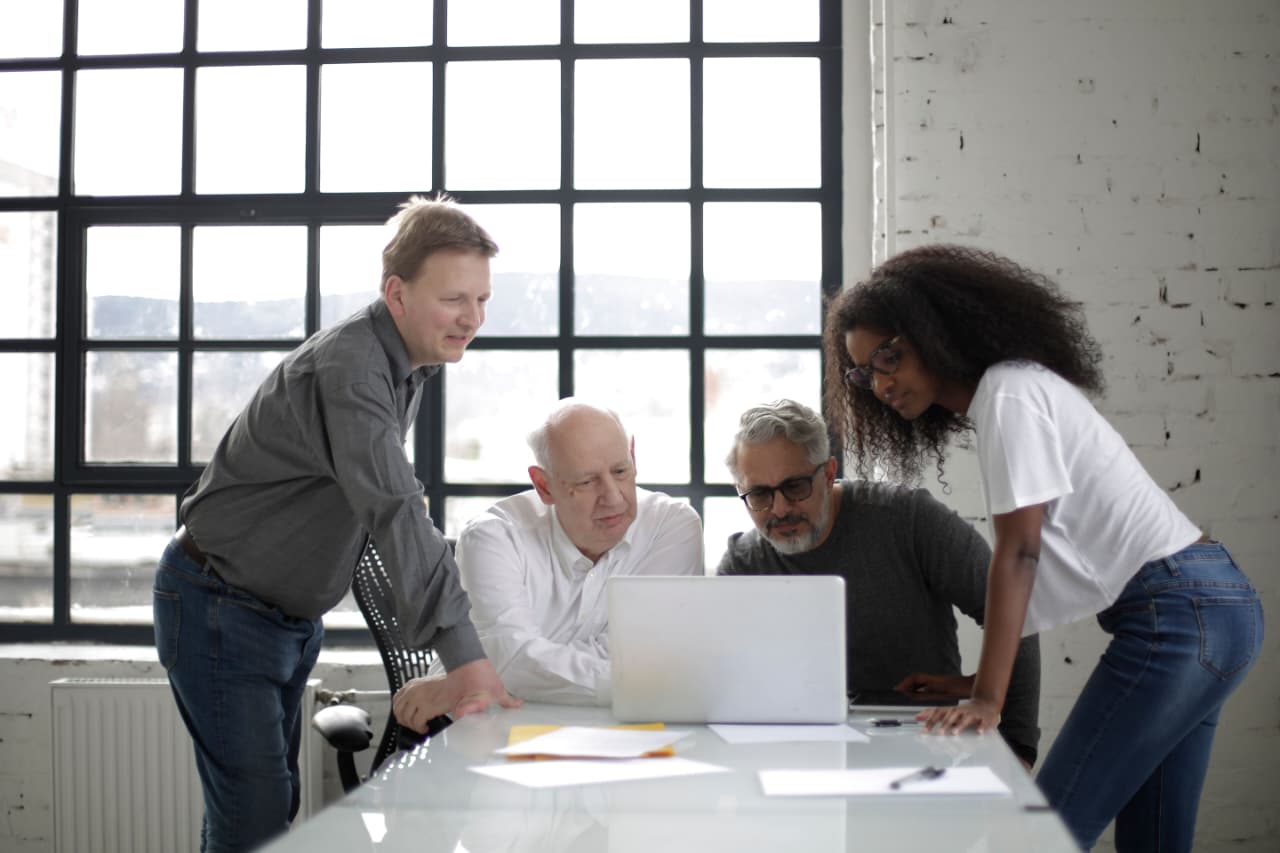 A small team reviewing work together at a table by a large window